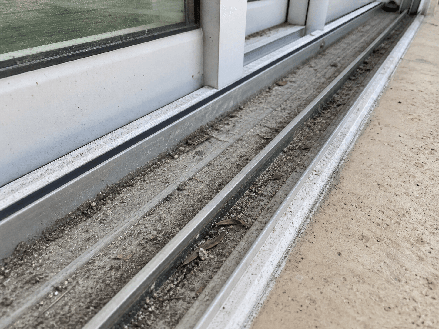 Before track cleaning example showing sand, dust, and debris in a sliding door track at a South Florida property